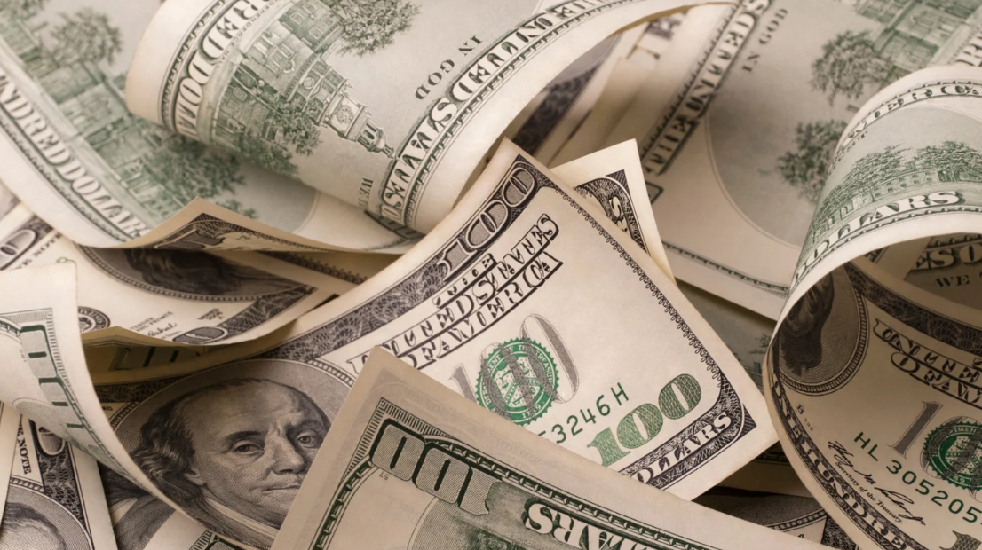 A close-up of multiple U.S. one-hundred dollar bills, featuring Benjamin Franklin’s portrait and overlapping details—a snapshot reminiscent of the vibrant energy found in Miami Dade, where business and pest control services thrive.